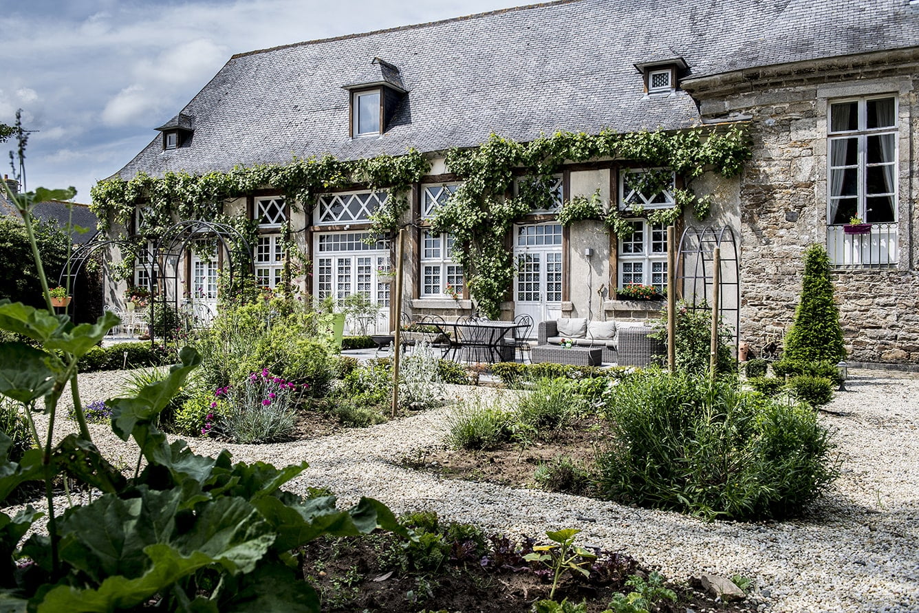 Jardin aménagé avec maison en pierre en deuxième plan par Architecte paysagiste